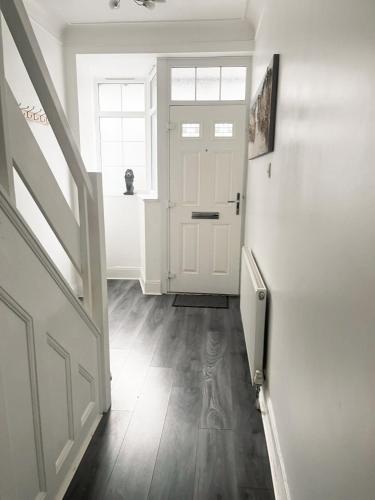 a hallway with a white door and a wooden floor at Large 3 Bedroom Home, Sleeps 7, Ideal for Families & Contractors, Long-Stay Friendly, Hosted by Clark Property Estates in Southend-on-Sea