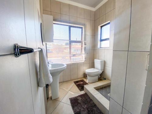 a bathroom with a toilet and a sink and a window at Alu Boutique Hotel and Conference in Roodepoort