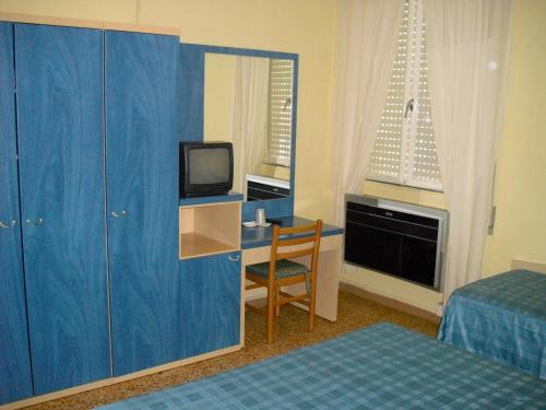 a hotel room with a desk with a tv and a bed at Hotel Garden in Tirrenia