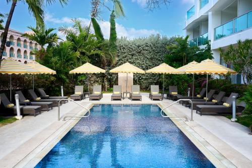 a pool with chairs and umbrellas next to a building at The Rockley by Ocean Hotels - Breakfast Included in Bridgetown