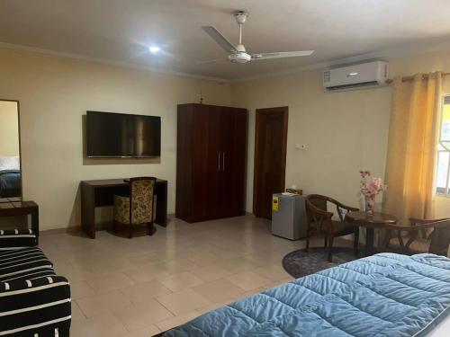 a bedroom with a bed and a tv and a table at Amoaba's Inn in Akropong