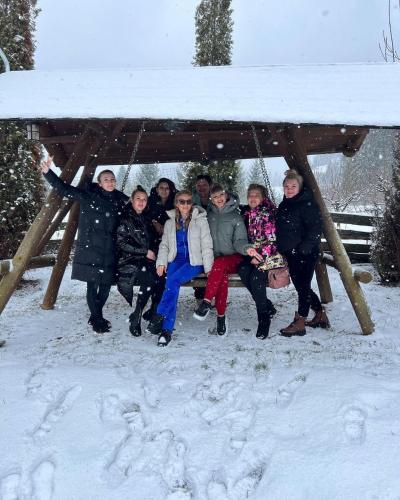 a group of people sitting on a swing in the snow at Blumenhof Bucovina in Voronet