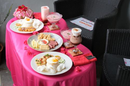 a pink table with plates of food on it at The Garden Suites New in Solo