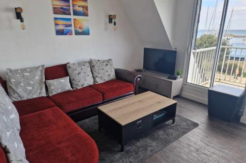 a living room with a red couch and a tv at Quiberon appartement vue mer - accès plage in Quiberon