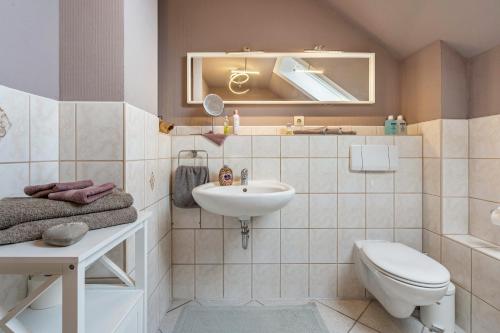 een badkamer met een wastafel, een toilet en een spiegel bij Fewo Omatina in Bannewitz