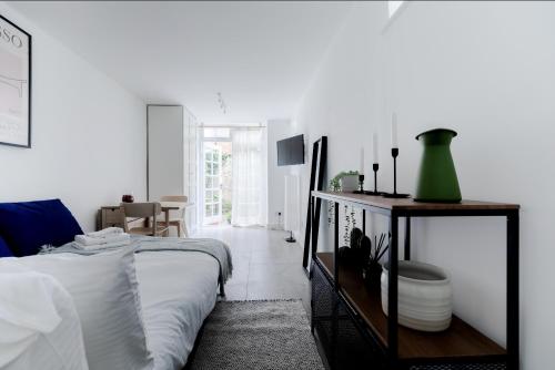 een witte slaapkamer met een bed en een tafel bij Charming Hampstead Garden Studio in Londen
