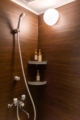 a bathroom with a shower with bottles on the wall at Elena Premium Namba Stay in Osaka