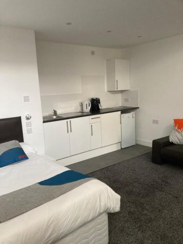 a bedroom with a bed and a kitchen with white cabinets at Palatine Aparthotel in Liverpool