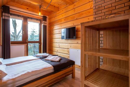 Dormitorio con cama y TV en una cabina en Rusińska Osada 36 Apartments en Bukowina Tatrzańska