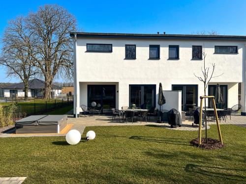 a white house with a yard with a playground at Luxus-Ferienhaus CASA SOL in Göhren-Lebbin