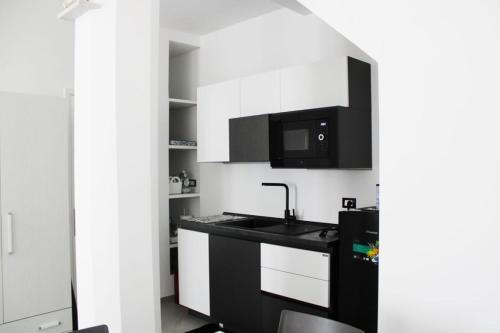 uma cozinha com armários brancos, um lavatório e um micro-ondas em San Leonardo Guest House em Castelbuono