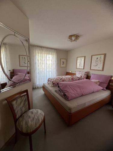 een slaapkamer met een bed, een spiegel en een stoel bij Wohnung Sonnenblume in Langenargen