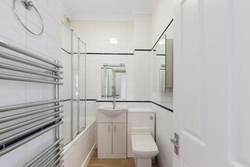 een witte badkamer met een toilet en een wastafel bij Exclusive Mayfair Apartment Suite in Londen