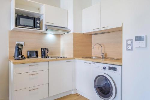 une cuisine avec une machine à laver et un lave-linge dans l'établissement OVELIA Fréjus - La Villa Marina, à Fréjus