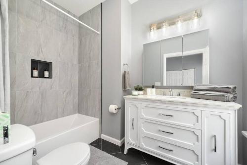 a white bathroom with a tub sink and a toilet at Luxury Living in Lawrenceville! in Pittsburgh