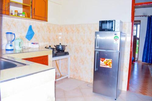 a kitchen with a refrigerator with a microwave on top at The Bay House in Homa Bay
