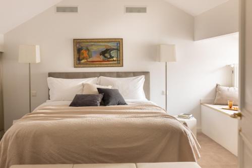 a white bedroom with a large bed with two lamps at The Hamlet - Luxury Serviced Apartments in Geneva