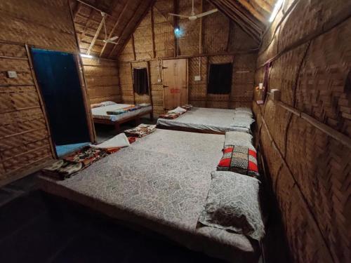 Habitación con 3 camas en una cabaña de madera en Hill Stone View Hampi en Hampi