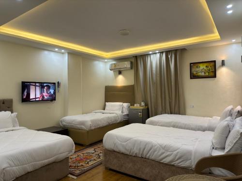 Habitación de hotel con 3 camas y TV. en Pyramids Gardens Hotel - فندق حدائق الاهرام, en El Cairo