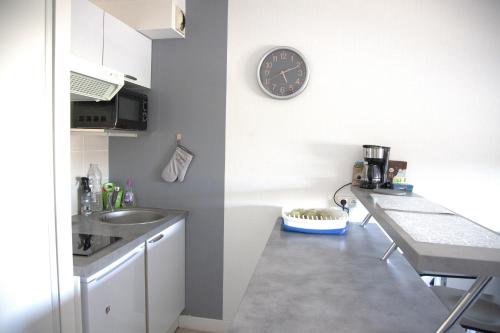 a kitchen with a sink and a clock on the wall at Atlantis - Studio - parking - lumineux in Vannes