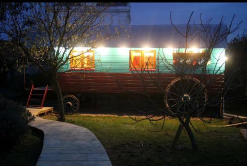 une maison avec un wagon dans la cour la nuit dans l'établissement Roulotte "Grain de Folie", à Waben