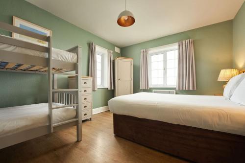 a bedroom with two bunk beds and two windows at Oystercatcher Apartments in Polzeath
