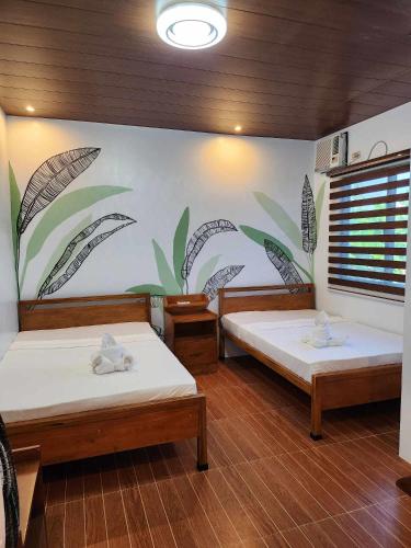 two beds in a room with a mural on the wall at BALAI MALINAWON - Balai 1 in General Luna