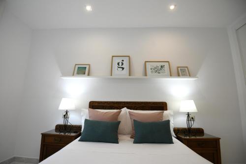 um quarto com uma cama branca com almofadas e 2 candeeiros em Coqueto apartamento en Raxó, Sanxenxo em Raxó