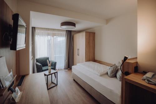 a bedroom with a bed and a chair and a window at Boutique Hotel Diana in Bad Füssing