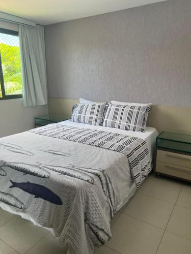 um quarto com uma cama grande com lençóis brancos e almofadas em Carneiros Beach Resort - Flat 205-A em Praia dos Carneiros