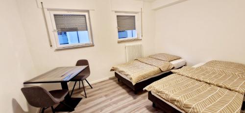 - une chambre avec 2 lits, un bureau et 2 fenêtres dans l'établissement Apartments EFDE GmbH Ferienwohnung, à Heilbronn