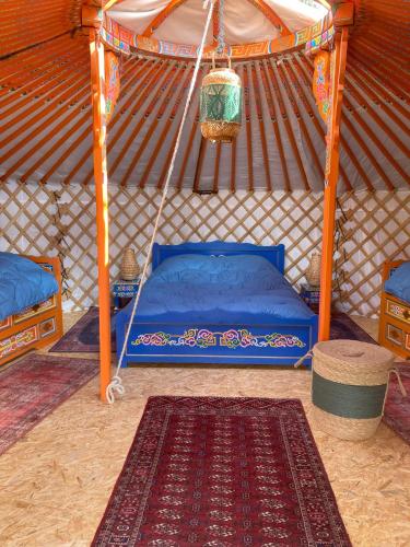 - une chambre avec un lit bleu dans une yourte dans l'établissement La Yourte de la Mariotte, à Montredon