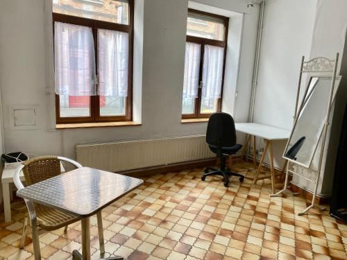 a room with a table and a desk and two windows at Lille ma ville in Lille