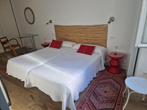 um quarto com uma grande cama branca com almofadas vermelhas em Santika em Saint-Jean-de-Luz