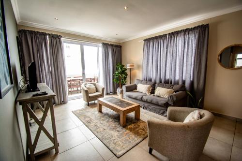 un soggiorno con divano, sedie e TV di Long Beach Selfcatering Namibia a Langstrand
