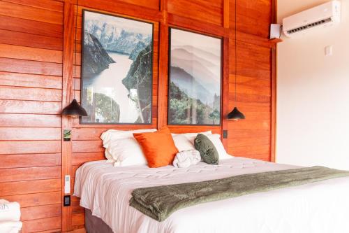 un letto in una stanza con due finestre di Khaya Chalés - Chalés de Luxo na Serra para Casais com Hidro a Jaboticatubas