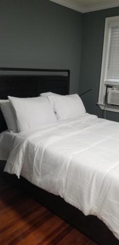 - un lit avec des draps et des oreillers blancs dans une chambre dans l'établissement A comfy place in queens, à Cambria Heights