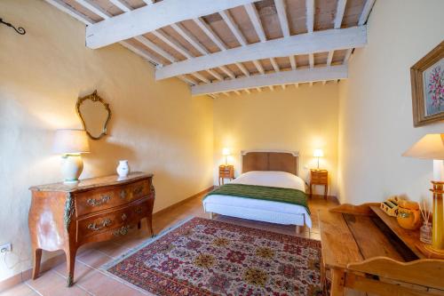 une chambre avec un lit et une commode en bois dans l'établissement Exceptionnel ! Mas provençal, à Montségur-sur-Lauzon