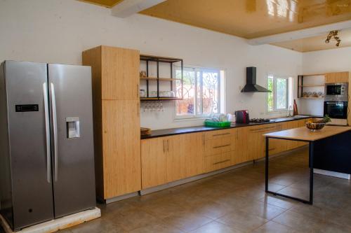 a kitchen with a stainless steel refrigerator and wooden cabinets at 3 bedrooms villa with private pool terrace and wifi at Antisiranana 5 km away from the beach in Antsiakambony