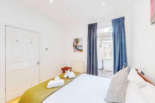 Un dormitorio con una gran cama blanca y una ventana en Cosy 2Bed garden flat in Wimbledon near the tube en Londres