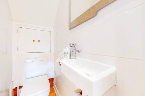 Baño blanco con lavabo y aseo en Cosy 2Bed garden flat in Wimbledon near the tube en Londres