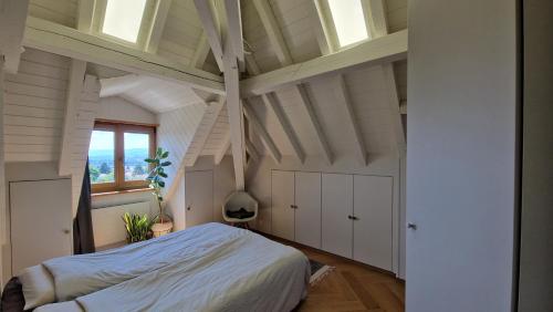 an attic bedroom with a bed and a window at Attic Apartment 2 Bedrooms in Crissier