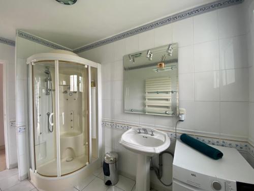 La salle de bains blanche est pourvue d'un lavabo et d'une douche. dans l'établissement Résidence des Rhodos, proche Lorient, à Caudan