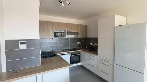 une cuisine avec des appareils électroménagers blancs et des armoires en bois dans l'établissement Appartement Le Novea standing pour 2 à 4 personnes, à Andernos-les-Bains