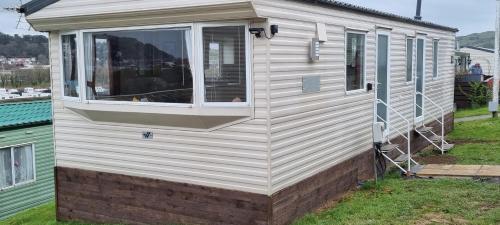 a white house with a window on the side of it at Light and Airy 2 Bedroom Mobile Home in Aberystwyth