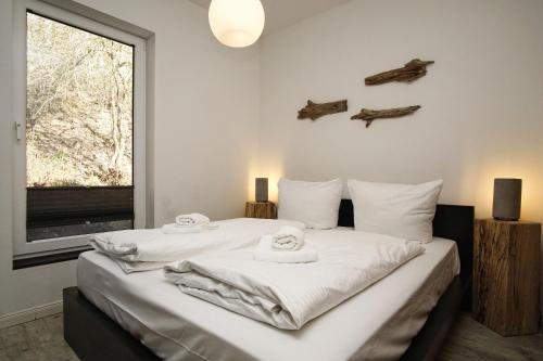 a bedroom with a large white bed with towels on it at naturnah, mit Terrasse, Garten und Meerblick - Ferienwohnung auf dem Teschenberg in Middelhagen