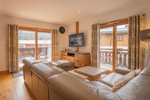 un salon avec un canapé et une grande fenêtre dans l'établissement Grand Paradis- Modern 3 bedroom apartment with spectacular views, à Chamonix-Mont-Blanc