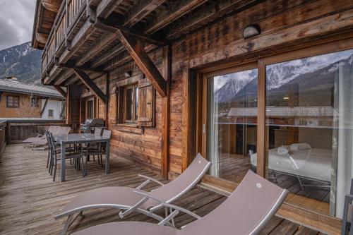 eine Terrasse mit Stühlen, einem Tisch und einem Bett in der Unterkunft Grand Paradis- Modern 3 bedroom apartment with spectacular views in Chamonix-Mont-Blanc