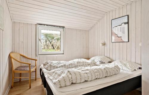 a bed in a room with a chair and a window at Nice Home In Nørre Nebel With Sauna in Nørre Nebel