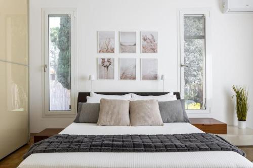a bedroom with a large bed with two windows at [Villa Fenice] Swimming Pool, big garden & Gym in Nurachi